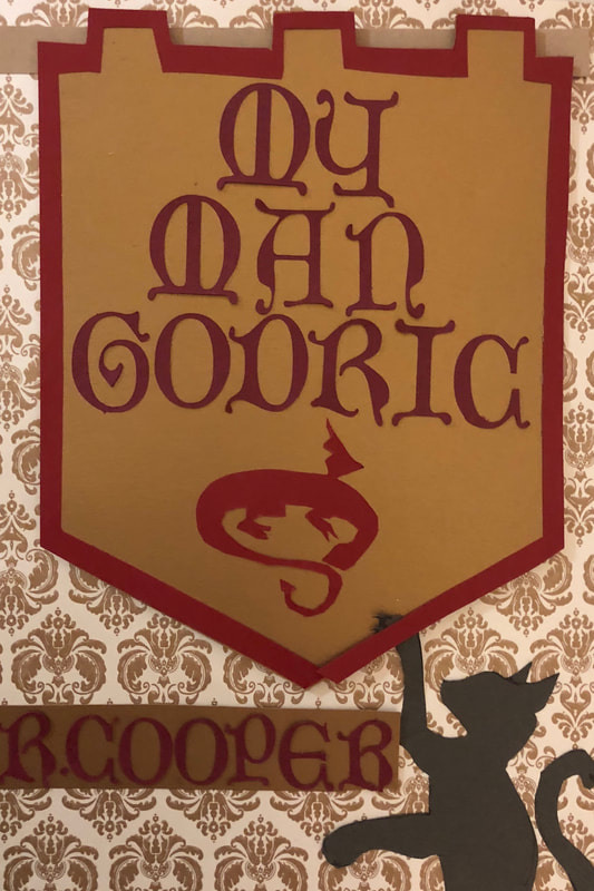 My Man Godric cover. a kitten playing with a heraldic seal of a red dragon